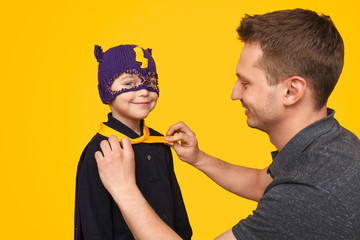 Father tying superhero cape on son