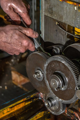 Gear metal wheels with worker hands in industrial machine close-up