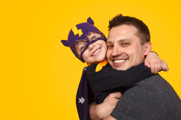 Cheerful father hugging superhero son