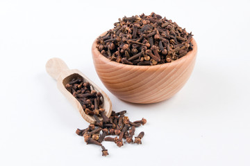 Cloves in wooden bowl and scoop isolated on white background. Closeup.
