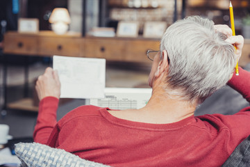 Concentrated pensioner sitting with bills and thinking
