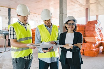 Team of builders engineers at construction site, reading blueprint. Construction, development,...