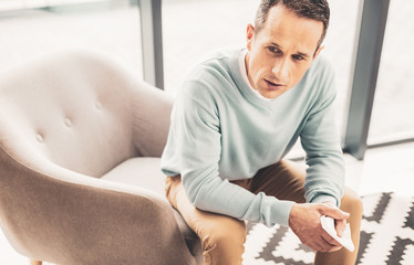 Concerned man feeling troubled sitting in armchair