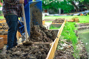 soil in rectangle flowerpot is prepared for homegrown vegetable planting in the garden.