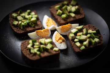 toast with avocado and egg on a black plate