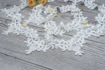 wooden background with spring flowers roses and lace ribbon. Happy womans day. The texture of lace on wooden background.