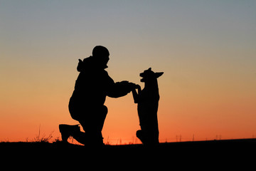 Fototapeta na wymiar A man and a dog against the backdrop of an incredible sunset