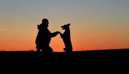 Fototapeta na wymiar A man and a dog against the backdrop of an incredible sunset