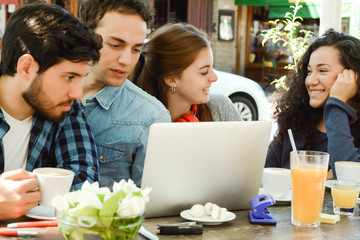 Friends meeting in a coffee shop with a laptop.