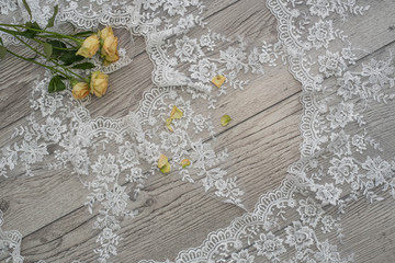 wooden background with spring flowers roses and lace ribbon. Happy womans day. The texture of lace on wooden background.