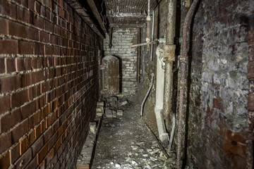 Looking down scary brick hallway to small open metal door of oven