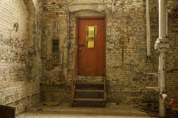 Orange door in scary cellar of brick walled basement