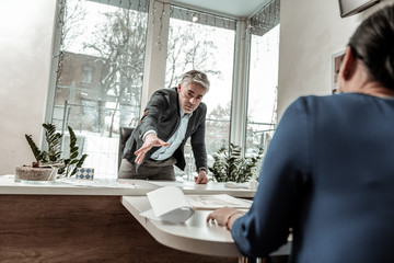 Tall grey-haired handsome man in eyeglasses feeling annoyed