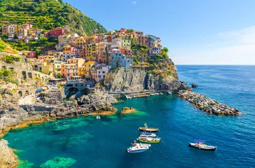 Zelfklevend Fotobehang Liguria Manarola traditioneel typisch Italiaans dorp in Nationaal park Cinque Terre, kleurrijke veelkleurige gebouwen huizen op rots klif, vissersboten op water, blauwe hemelachtergrond, La Spezia, Ligurië, Italië