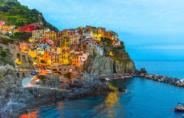 Fototapeta na wymiar Manarola traditional typical Italian village in National park Cinque Terre with colorful multicolored buildings houses on rock cliff and marine harbor, night evening view, La Spezia, Liguria, Italy
