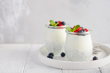 Chia seed pudding with fresh berries on a white wooden table, selective focus.