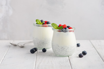 Chia seed pudding with fresh berries on a white wooden table, selective focus.