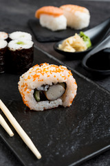 Sushi Set sashimi and sushi rolls served on stone slate 