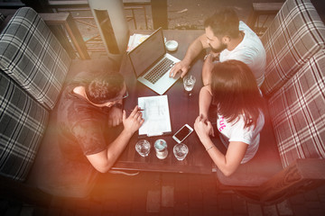 Businessmen discuss the deal and control it online, in a cafe on the street. A girl and two guys.