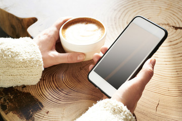 Closeup view woman hands using mobile smartphone and cup of coffee. Space mockup for design layout....