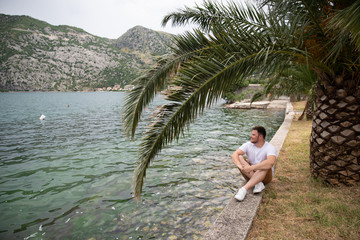 man sitting at seaside with beautiful view. mountains on background
