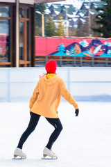 A young, slim girl in outdoor figure skating on a roller skating rink