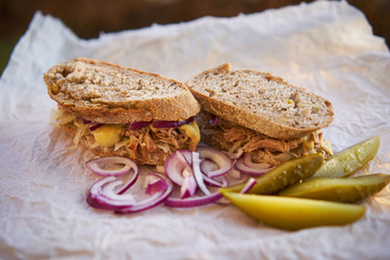 Close up picture of whole grain sandwich with pulled pork and sour cabbage and pickles served like light meal, fast food, street food packed in wrapping paper bistro. 