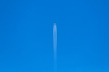 Plane against deep blue sky leaving white traces