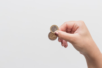 hand of woman holding two euro coins, 1 and 2 euros. White background