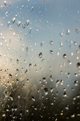 raindrops on window glass on background of cloudy sky