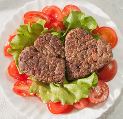 grilled burgers in the shape of a heart with a salad of tomato, top View