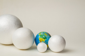 Four white balls of plastic, different sizes and globe lie in the plane of the blue background, in a dense composition, copy space.