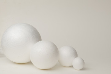 Four white balls of plastic, of different sizes lie in the plane of the blue background, in a dense composition, copy space.