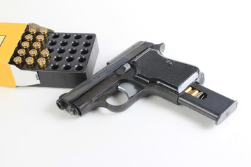 Small .25 caliber hand gun and open box of cartridges