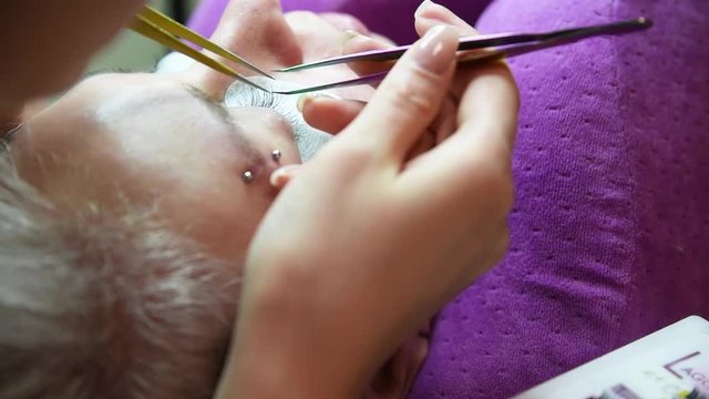 Beauty and fashion concept - Eye lash extension procedure. Young beautiful woman eye with long false eyelashes. Close up macro shot of fashion eyes in beauty salon.