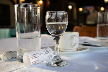Alcohol drink, cup of coffee and bill on table in restaurant
