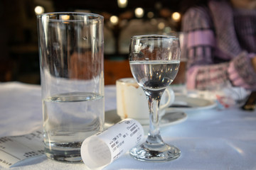 Alcohol drink, cup of coffee and bill on table in restaurant