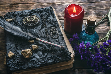 Spell book, magic potions and other various witchcraft accessories on the wizard table background.