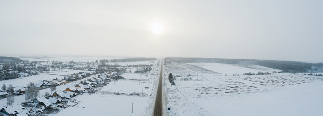 view from height, winter road with ice on the asphalt, trees under snow during the winter frost in Russia