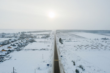 view from height, winter road with ice on the asphalt, trees under snow during the winter frost in Russia