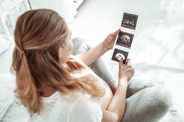 Light-haired pregnant woman sitting with crossed legs