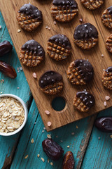 Raw vegan gluten and sugar free cookies with chocolate served with rolled oats, dates and salt on blue background