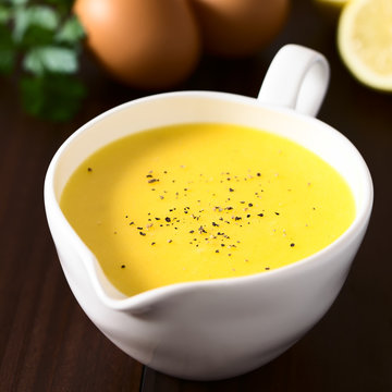 Hollandaise sauce, basic sauce of French cuisine, served in sauce boat with ground black pepper on top, photographed with natural light (Selective Focus in the middle of the sauce)