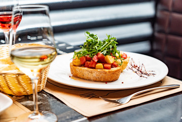 Traditional italian bruschetta with cherry tomatoes, cream cheese, peppers, arugula leaves and balsamic vinegar