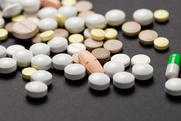 Obraz na płótnie Canvas Heap of colorful medication on black background.