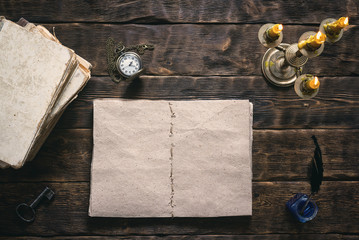 Open blank page book, old literature, pocket watch and a inkwell with quill pen on a writer wooden table background.