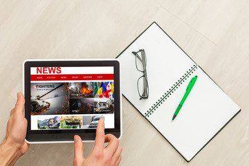 Man hands are pointing on touch screen device with business news.