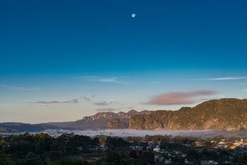 fog in the valley of Vinales with full moon palm trees and mountains