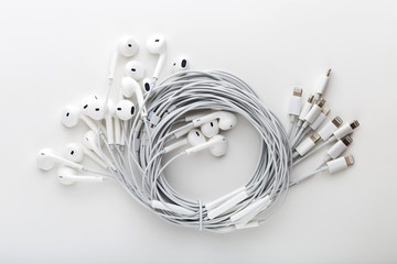 Headphones on a white background. Lots of headphones coiled together on a white background.