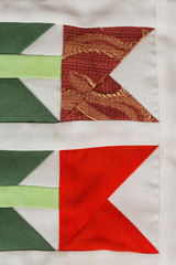 Fototapeta premium patchwork, sewing, fashion concept - macro on beautiful quilt sewn from scraps of colored cloths in feed of certain geometric shapes, close-up on different flaps of stitched material, flat lay.